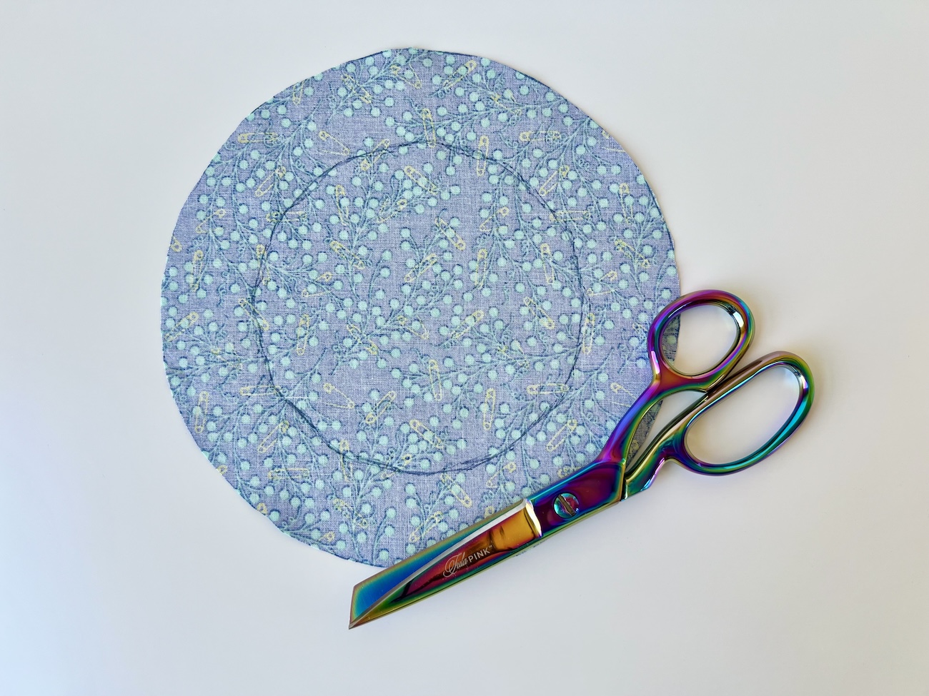 A cut out fabric circle with a pair of rainbow scissors