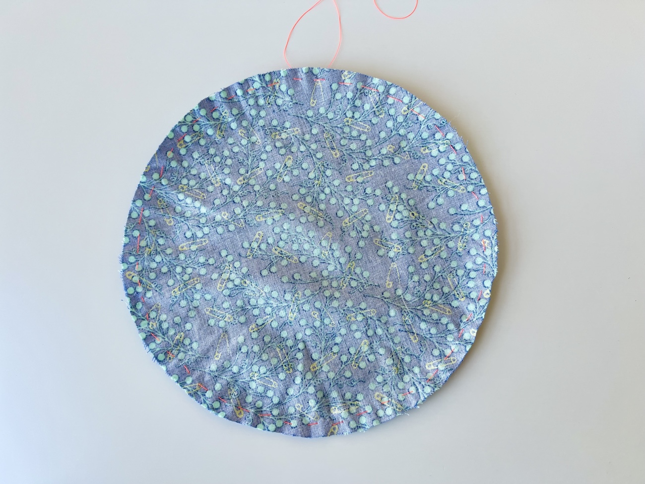 A circle of fabric with a gathering stitch sewn around the edge