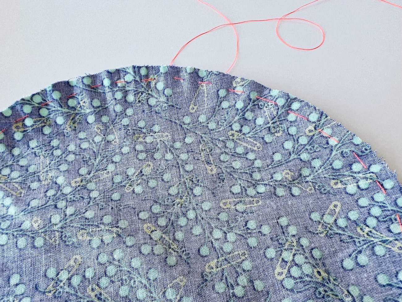 A close up of the gathering stitches sewn around the edges of the fabric circle